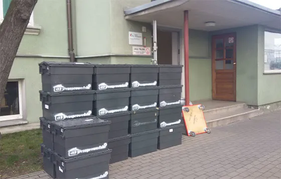 Plastikowe skrzynie przeprowadzkowe ustawione przed budynkiem Kolei Wielkopolskich